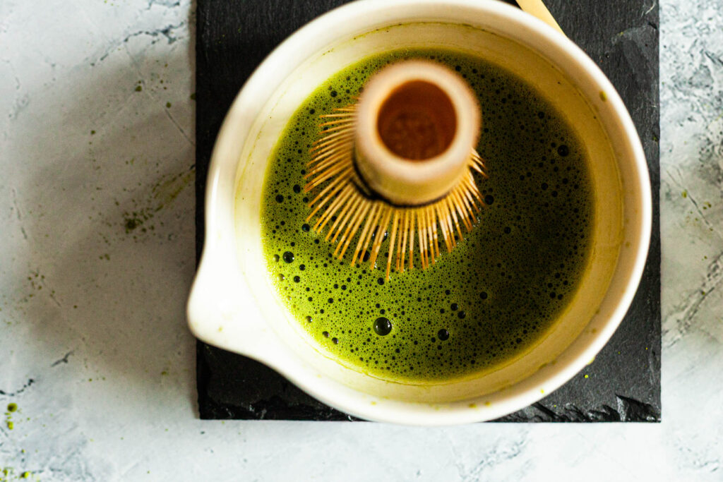Spieniona matcha w miseczce z bambusową trzepaczką chasen