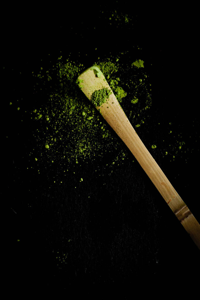 Zielona matcha na bambusowej miarce chashaku na ciemnym tle