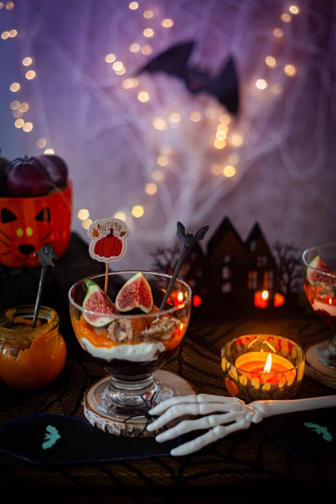 Deser z dynią, skyrem i figami w halloweenowej aranżacji z dyniami i świecą.